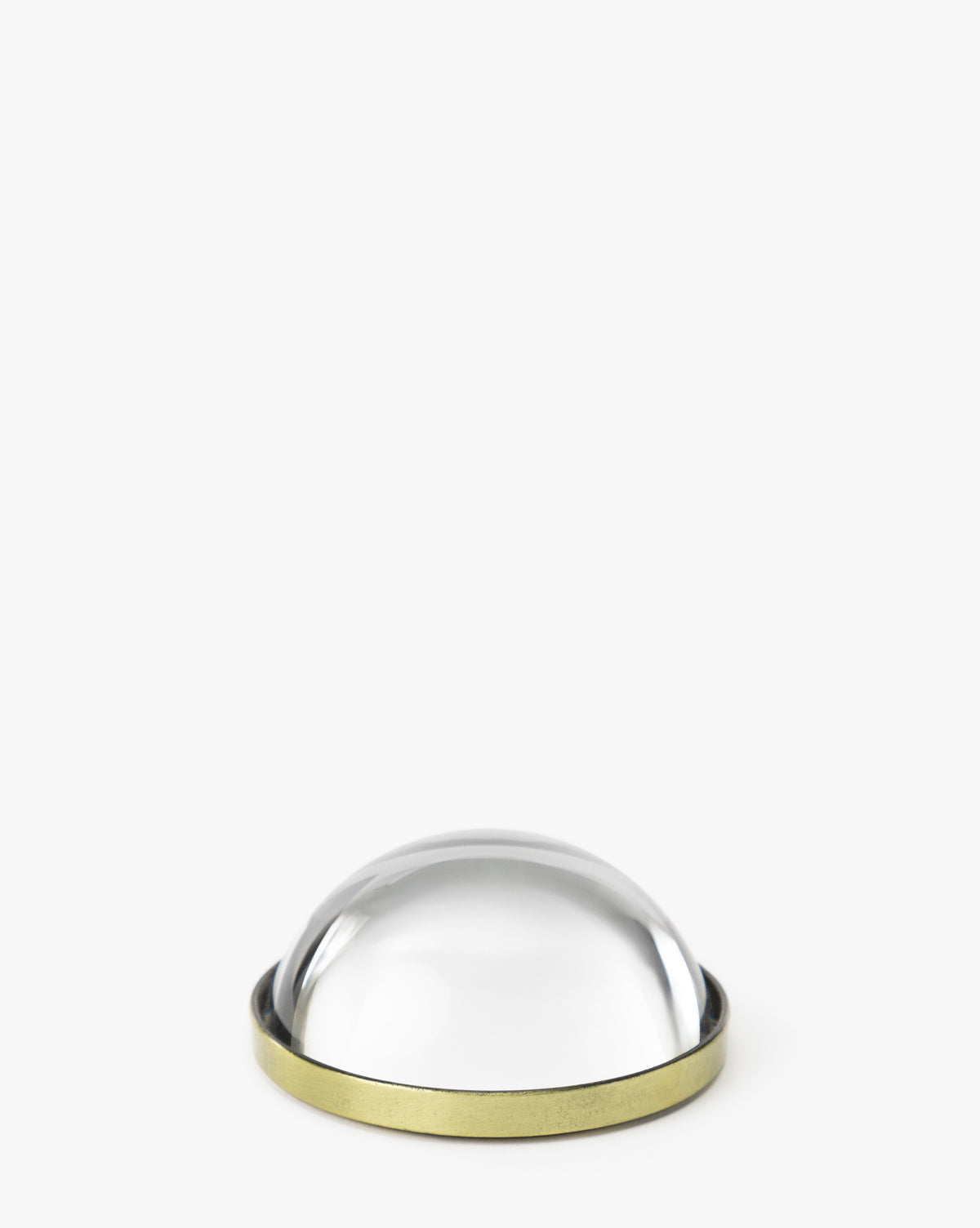 The Tatiana Glass Object is a clear dome magnifier with a brass-colored metal base, evoking vintage style, shown on a plain white background by McGee & Co.