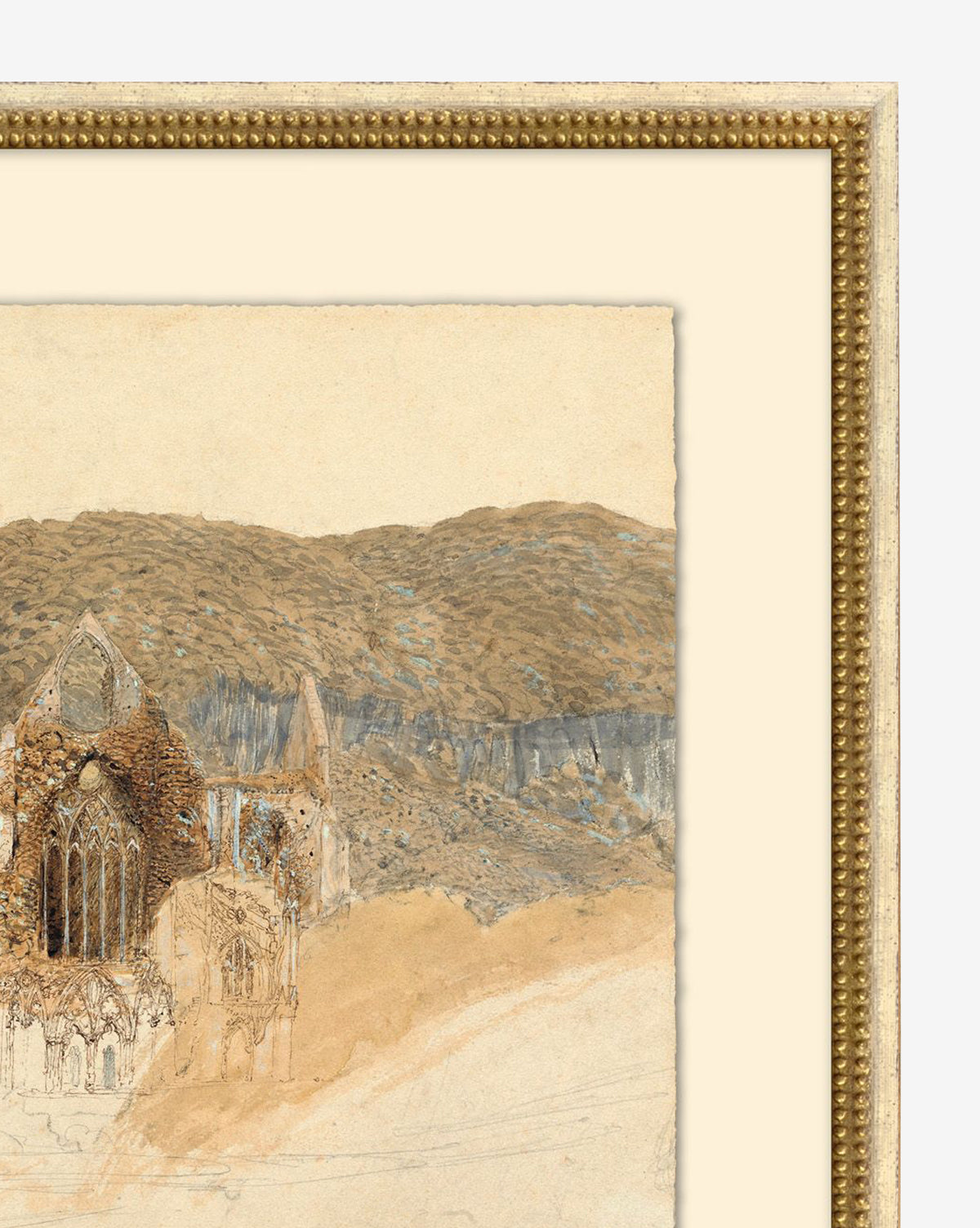Unveiling Foundations, a giclee print on watercolor paper, depicts a partial sketch of a ruined stone cathedral with pointed arches, set amid rolling hills and cliffs in brown and blue hues. The artwork is displayed in a gold-finished wood frame, by McGee & Co.