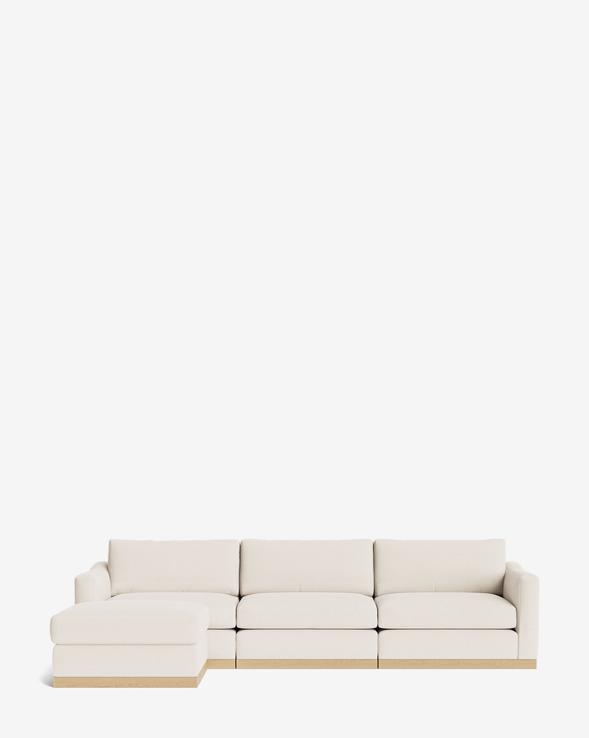 The Vernon Modular Sofa with Ottoman 121 features light beige upholstery, a low wooden base, and a left-side chaise lounge. Set against a plain white background, this modern sectional offers customizable fabric options to fit any style by McGee & Co.