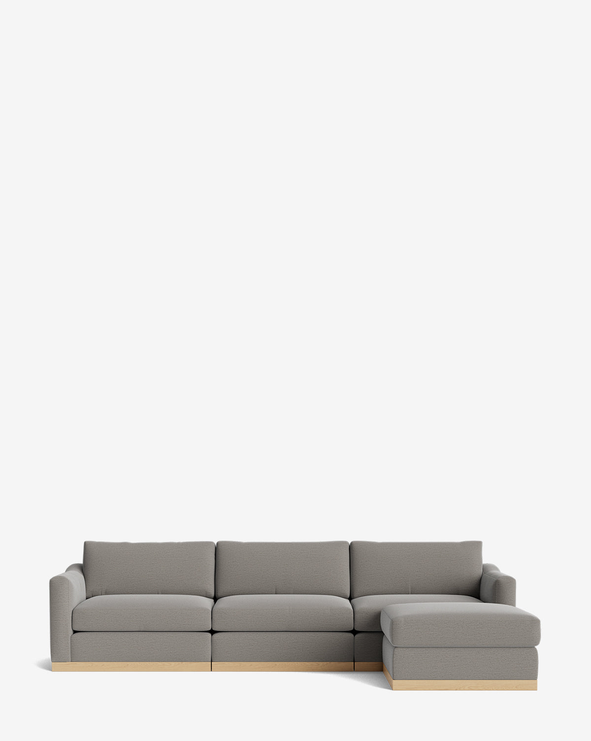 The Vernon Modular Sofa with Ottoman 121 is a modern gray sectional featuring three cushions, a right-side chaise lounge, and a light wooden base. Set against a white background, this customizable fabric sofa blends style and comfort seamlessly by McGee & Co.