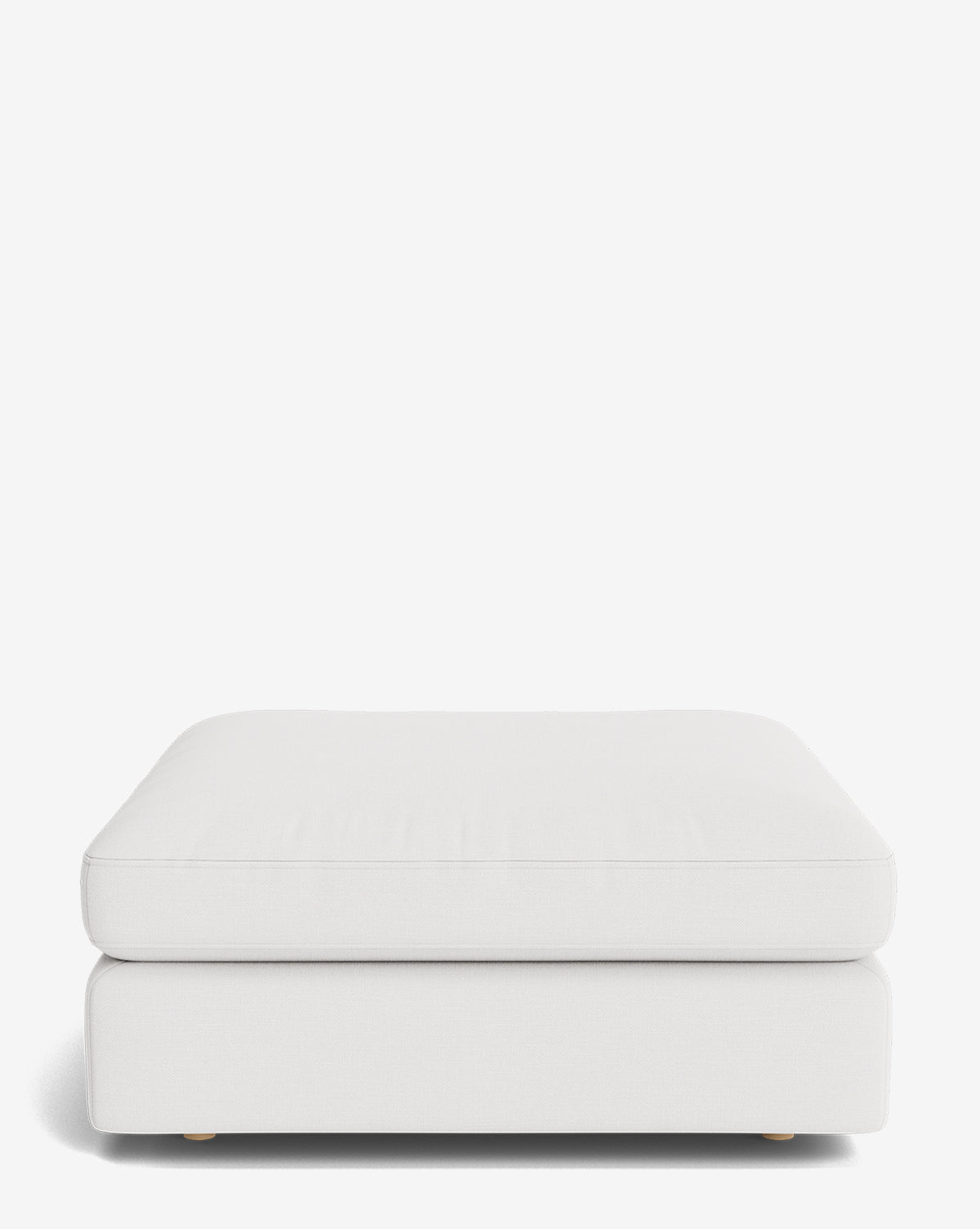 The Vivienne Modular Ottoman is a minimalist, rectangular white piece with a thick cushion, low rounded corners, and subtle short legs barely visible underneath, shown on a plain white background by McGee & Co.