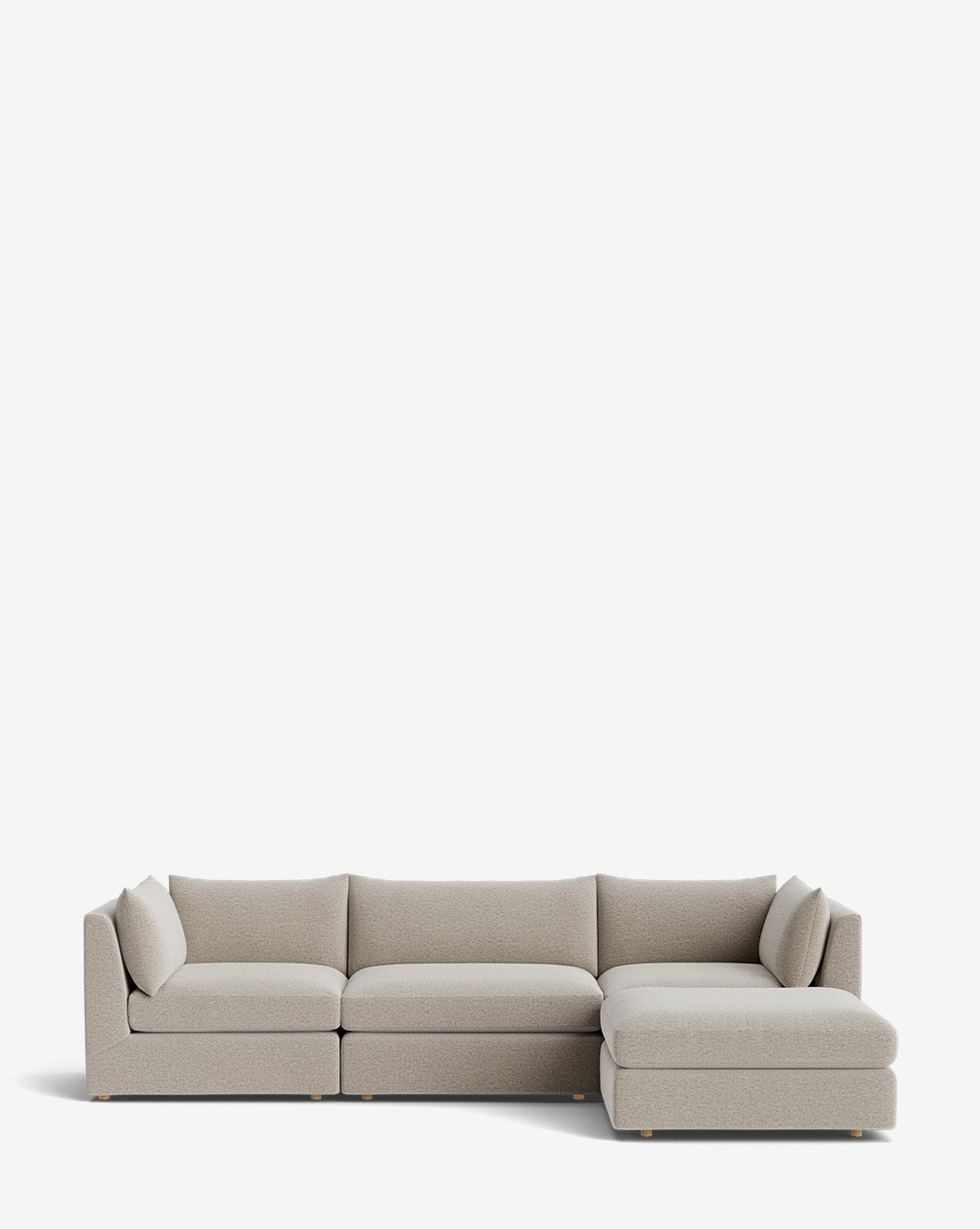 The Vivienne Modular Sofa with Ottoman is a modern, light gray, handmade L-shaped sofa featuring low backrests and armrests, plush cushions, and a right-side chaise lounge. Shown against a plain white background by McGee & Co.