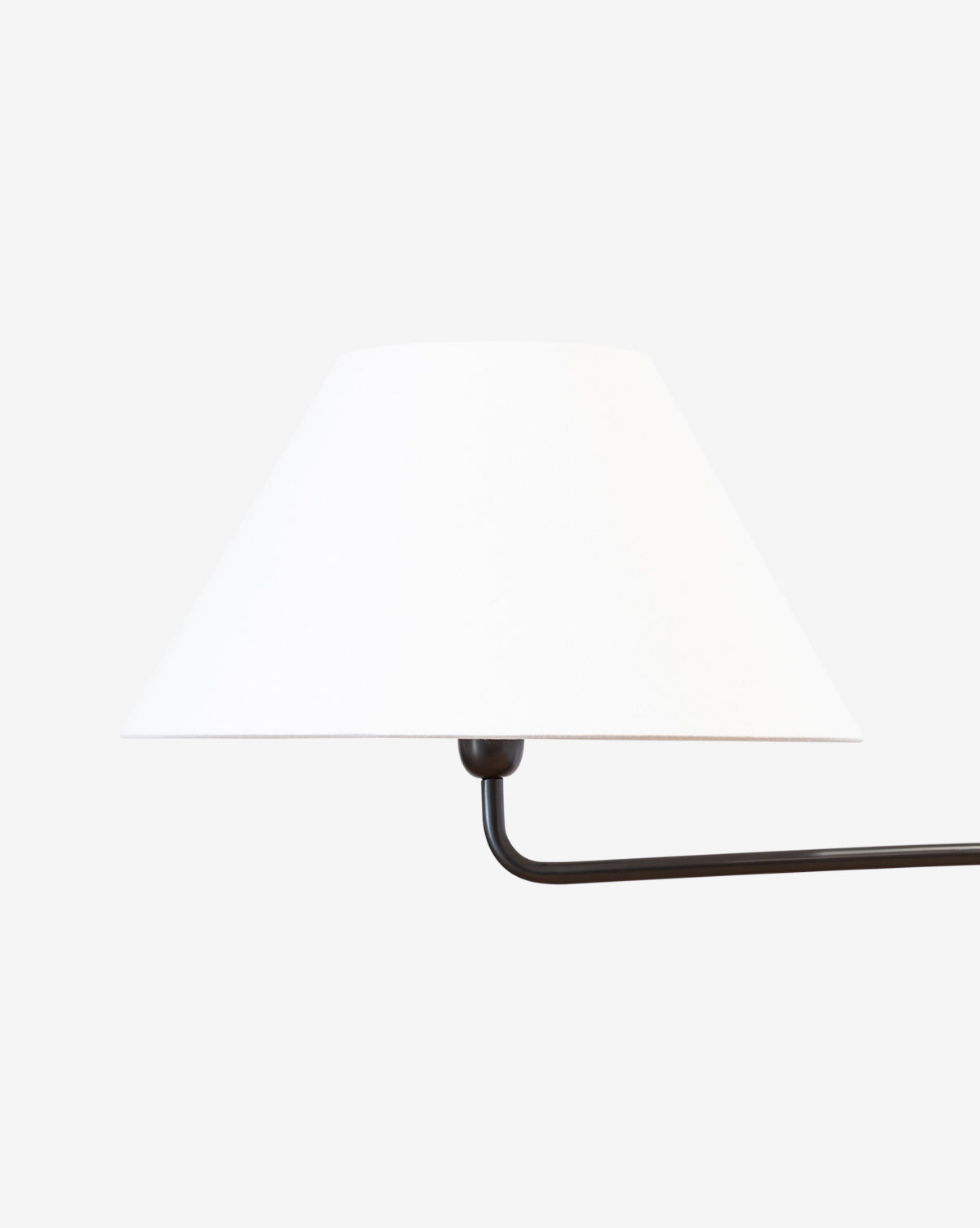 The Wainwright Swoop Floor Lamp features a minimal design with a white conical lampshade and a sleek black metal arm that extends horizontally, channeling vintage elegance against a plain, light background, by McGee & Co.