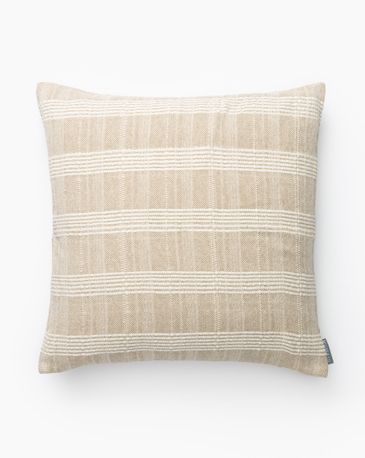 The Whitney Pillow Cover is a neutral cotton pillow cover with a rectangular shape, beige background, and horizontal white textured stripes. It features a small fabric tag on the lower right side, by McGee & Co.