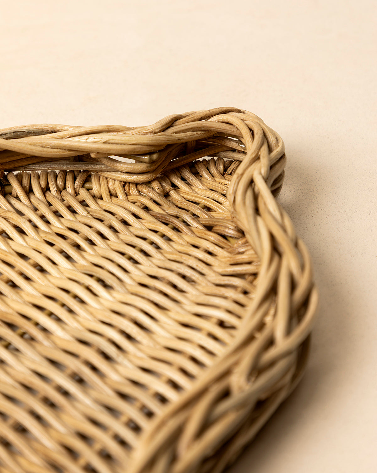 Close-up of the Wicker Bell Tray, featuring braided edges and intricate handwoven texture, set on a light beige surface—ideal for adding elegance to your holiday entertaining setup, by McGee & Co.