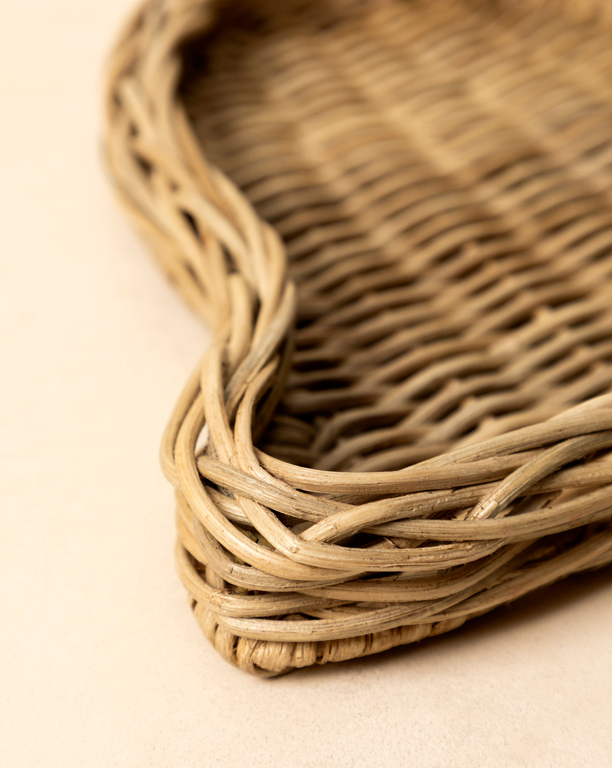 Close-up of the Wicker Bell Tray, showing its curved edges and detailed handwoven pattern in natural fibers—ideal for holiday entertaining on a light background, by McGee & Co.