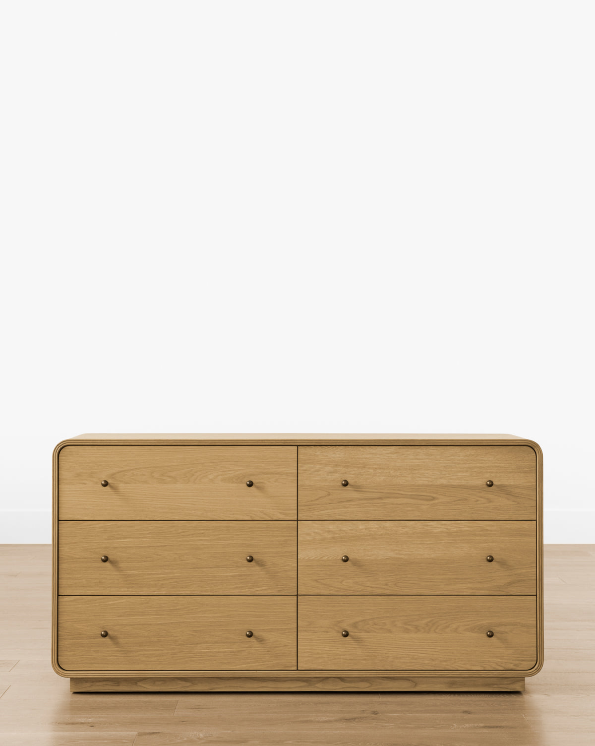 The Wilkins Oak Dresser, in a light finish with six drawers and small round knobs, stands on a hardwood floor against a white wall—ideal for enhancing your bedroom décor, by McGee & Co.