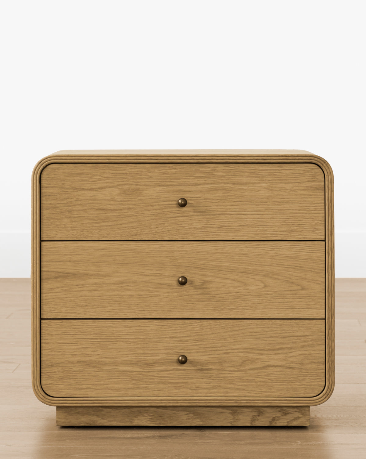 The Wilkins Oak Nightstand features a light wood finish, rounded edges, and a sleek wooden drawer with a single round knob—perfect for adding timeless style to any bedroom design, by McGee & Co.