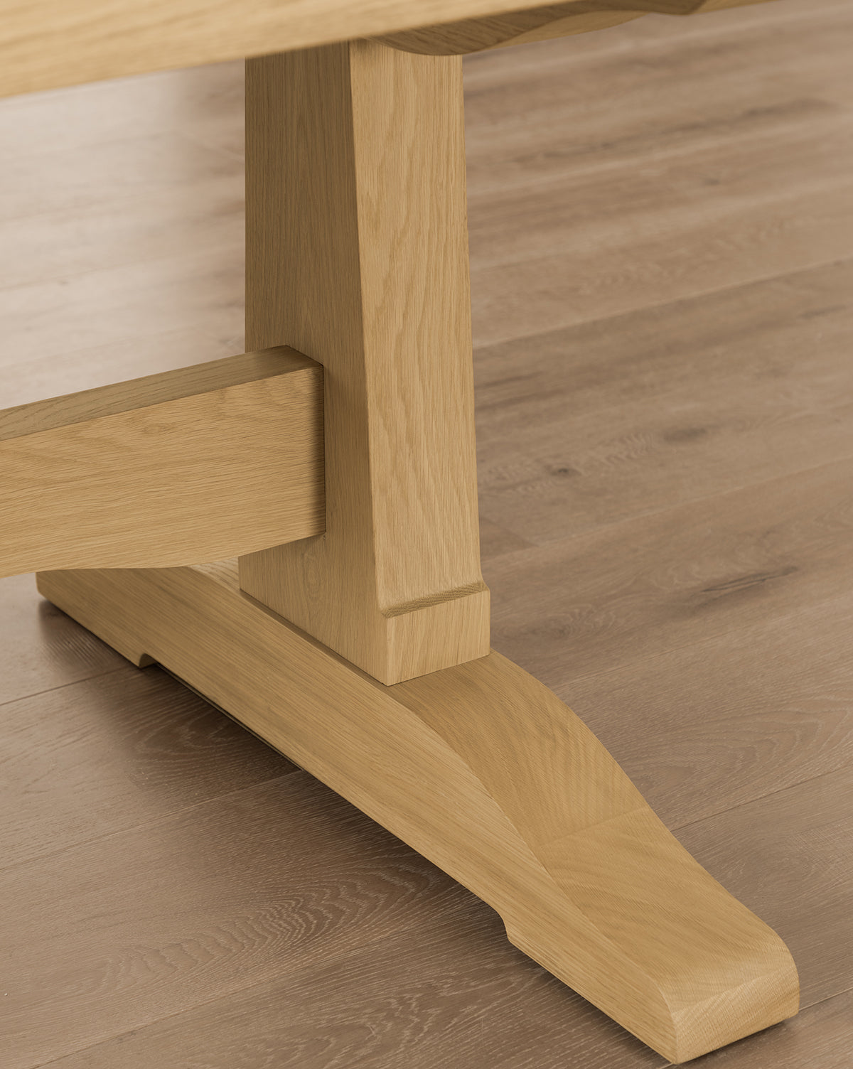 Close-up of the Wilton Dining Table’s wooden base and leg on a light wood floor, showcasing the grain and texture of its natural white oak finish, by McGee & Co.