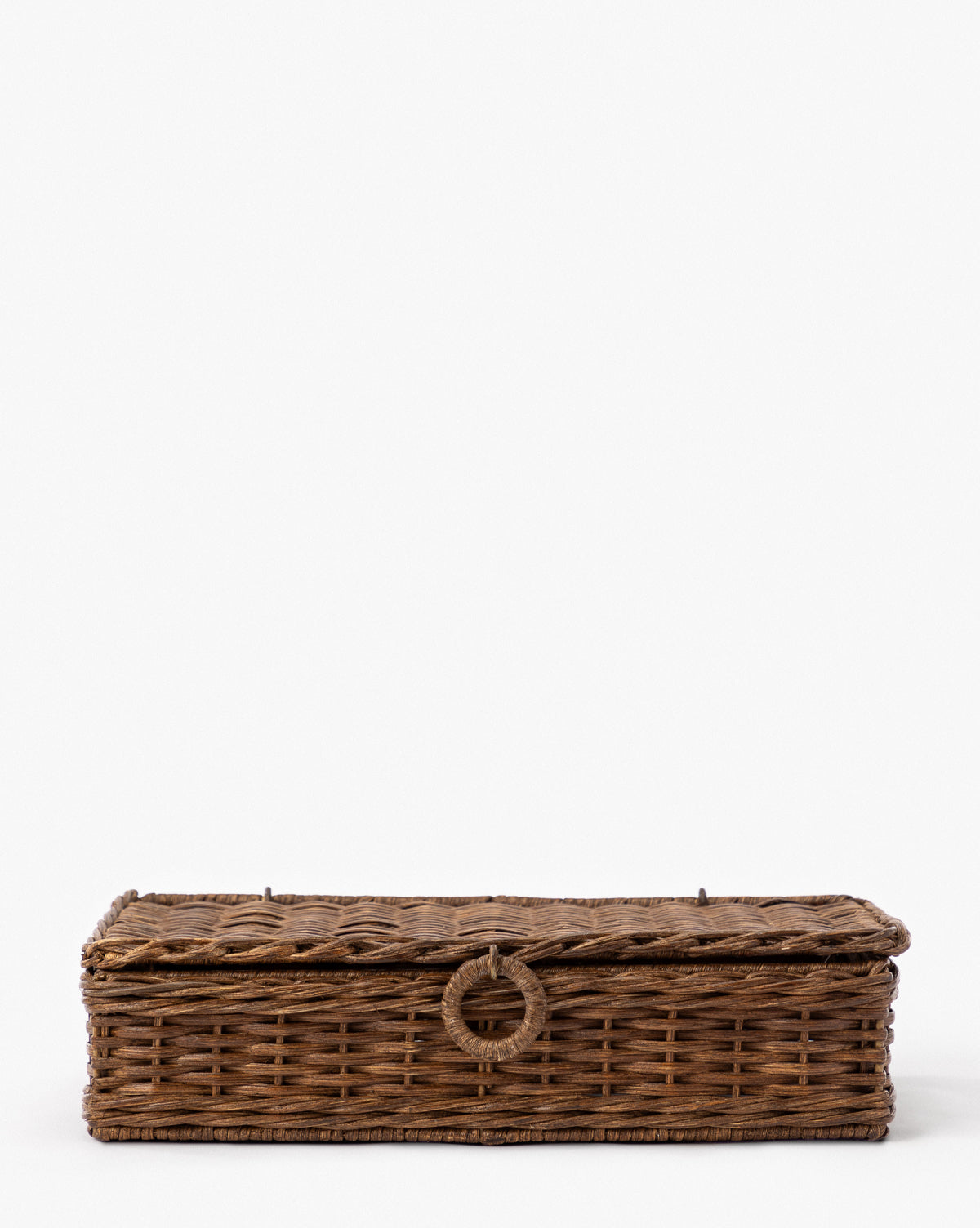 The Windmere Woven Box is a rectangular, flat, brown wicker box with a hinged lid and a circular front handle, shown against a plain white background by McGee & Co.