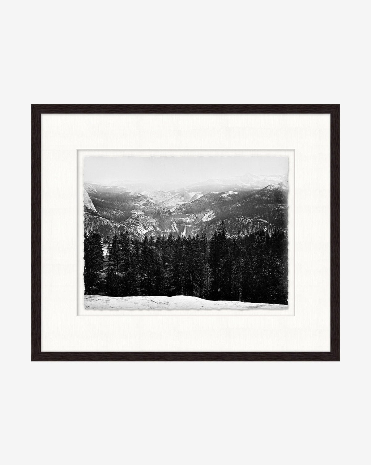 Winterscape is a black and white photo of snow-covered Rocky Mountains with pine trees and distant hills, presented in a dark wooden frame with a white mat.