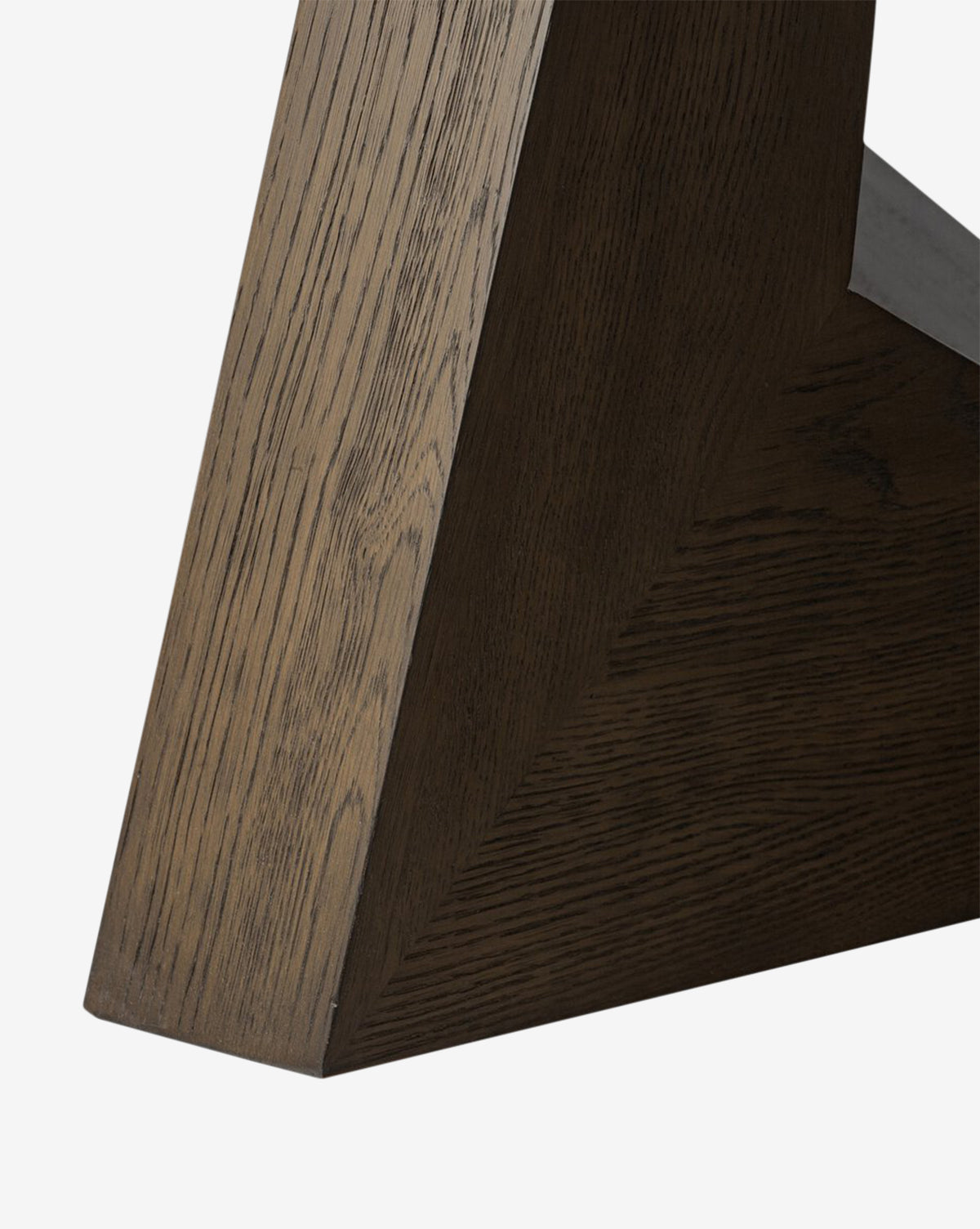 Close-up of a Yvonne Dining Table leg showcases its oak woodgrain detail, angled design, and rich dark finish against a plain white background by McGee & Co.