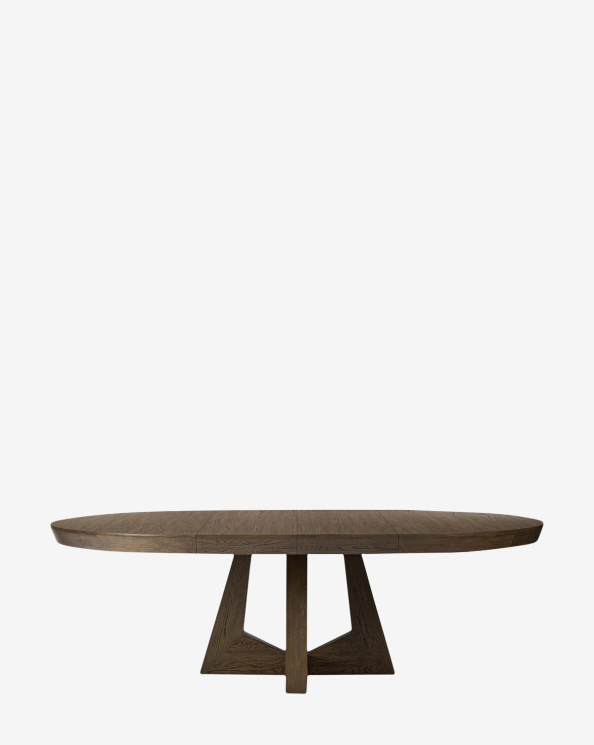 The Yvonne Dining Table showcases an oval silhouette in oak woodgrain with a geometric pedestal base, ideal for adding elegance to your dining area amidst a minimalist white setting, by McGee & Co.