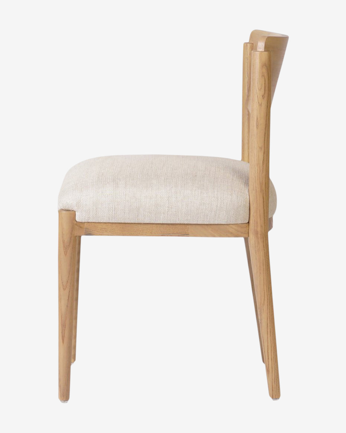 Side view of the Reverie Dining Chair featuring a light upholstered seat, angled backrest, and minimalist wood frame, shown against a plain white background, by McGee & Co.