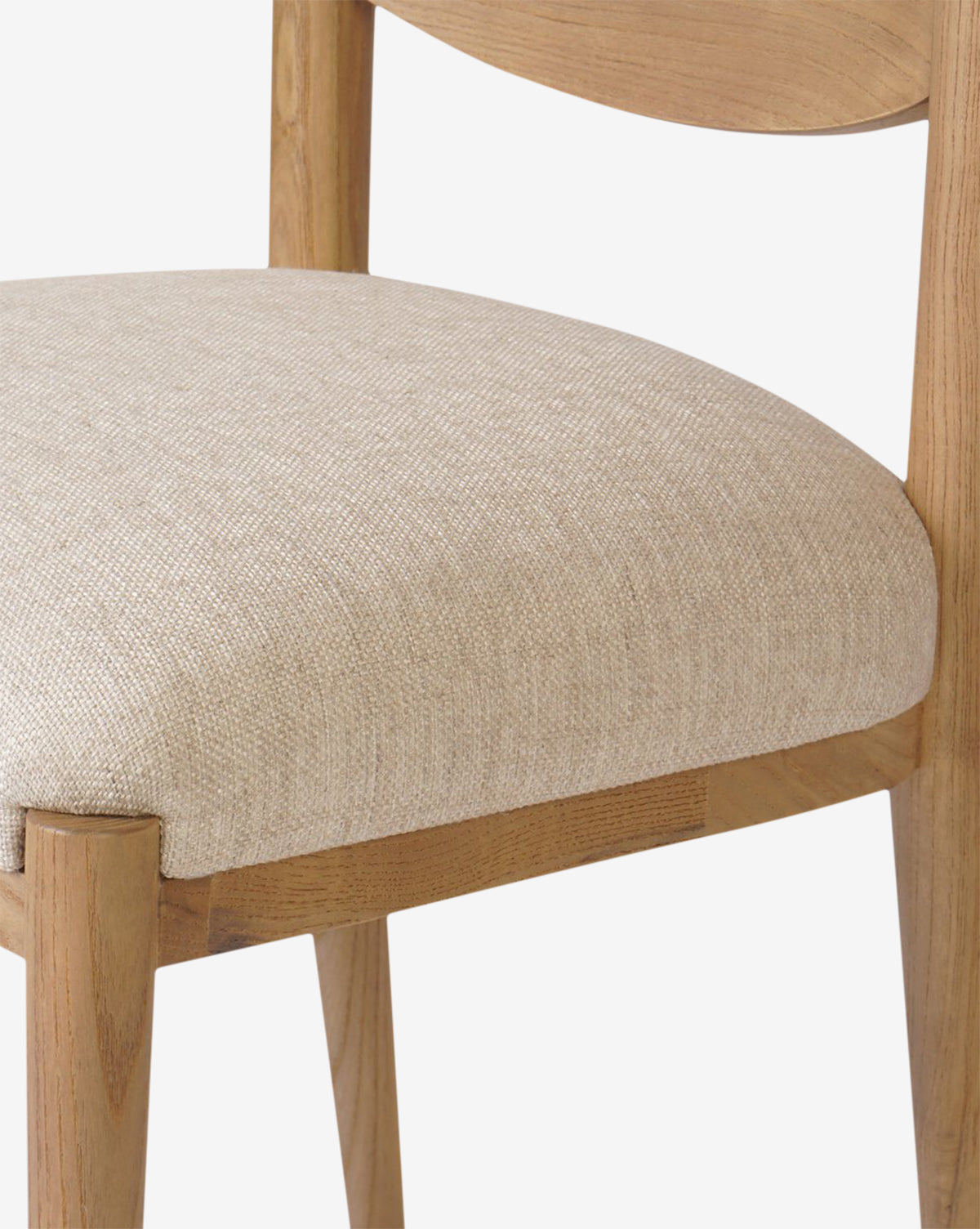 Close-up of the Reverie Dining Chair showcases its smooth wood frame and light beige, textured upholstered seat. Its simple, modern design is set against a plain white background, by McGee & Co.