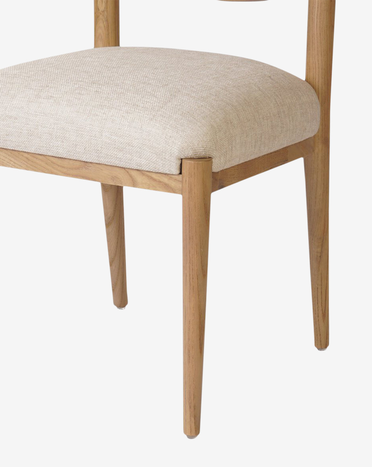 A close-up of the Reverie Dining Chair showcases its sturdy wood frame, beige upholstered seat cushion, angled legs, and sleek modern design set against a white background, by McGee & Co.